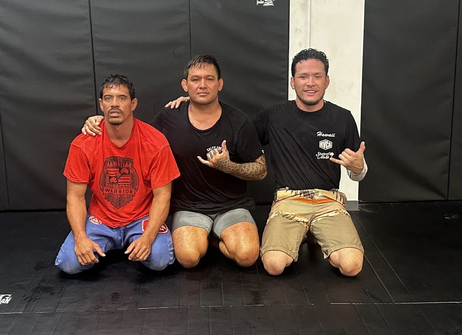 Three 808 Top Team grappling coaches kneeling on the mats at Iron Kingz