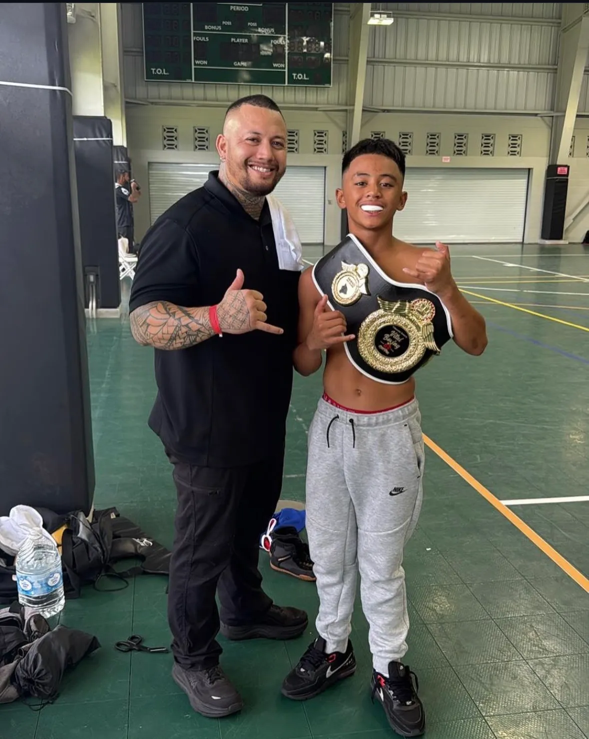 Iron Kingz founder and head boxing coach with a young champion holding a title belt