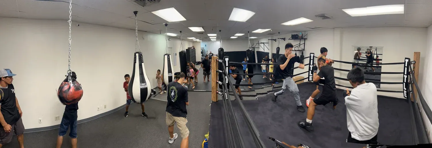 Panorama of the Iron Kingz training floor with heavy bags and the ring
