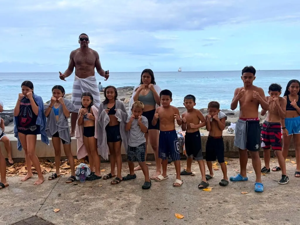 Iron Kingz kids and their coach at the beach in Hawaii, fists up