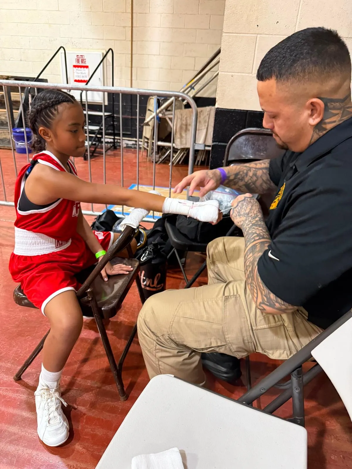An Iron Kingz coach taping a young boxer’s hands before a bout