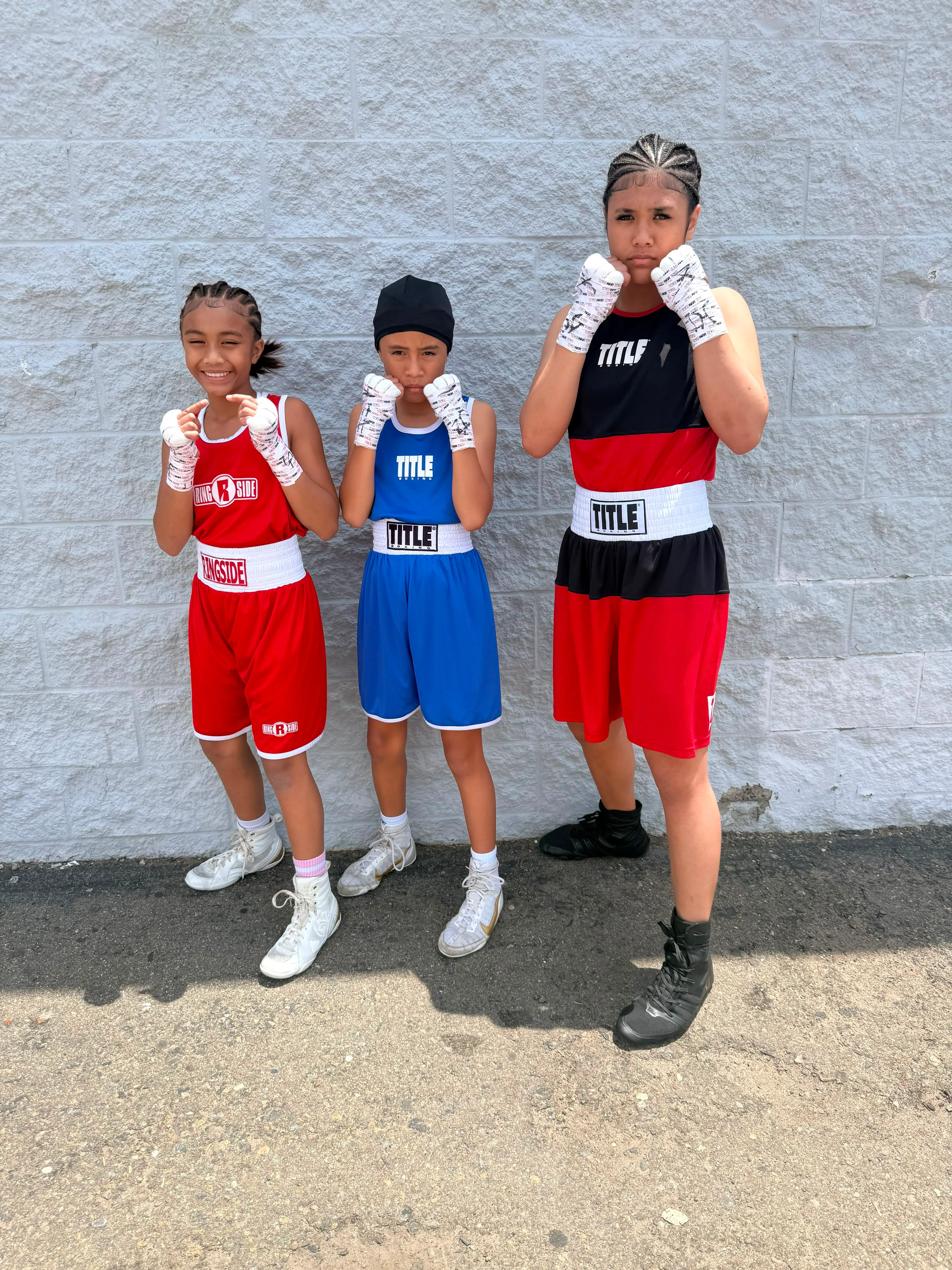 Three young Iron Kingz boxers in competition gear posing together