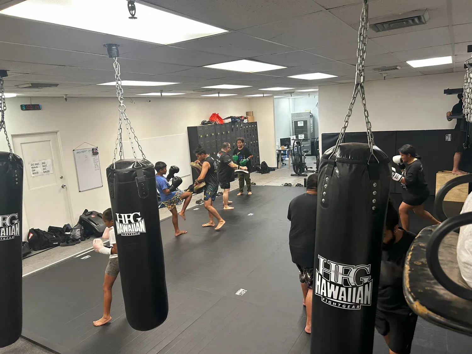 Fighters training on a row of hanging heavy bags in the Iron Kingz Muay Thai room